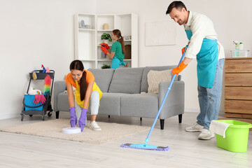 Team of young janitors cleaning in room
