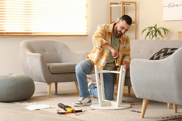 Young man with screwdriver assembling small table at home