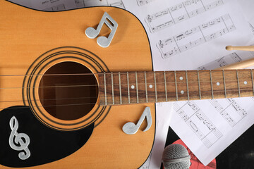 Guitar with note signs and music sheets, closeup