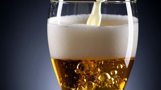 Glass of beer being poured with frothy head