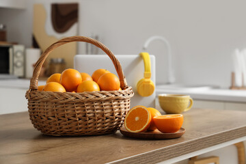 Wicker basket with oranges on table in kitchen