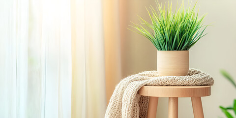A serene indoor scene featuring a potted plant on a wooden stool, complemented by a cozy blanket and soft natural light.