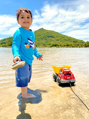 Happy boy playing in a crystal clear lagoon next to the sea with mountains and tropical vegetation of the Atlantic forest in the background in harmony with green and blue. Summer and joy