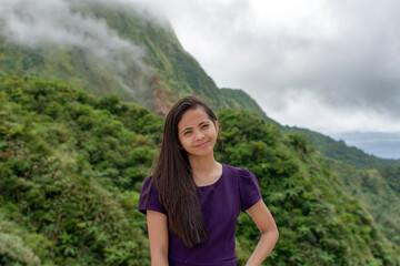 Naklejka premium Portrait of a beautiful young Filipina woman against the backdrop of tropical mountains covered with clouds