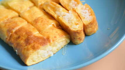 roll omelette stuffed with chesse and rice on blue plate, delicious food in the morning