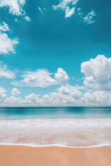 Fototapeta premium Sandy beach with gentle waves, clear blue ocean and sky.