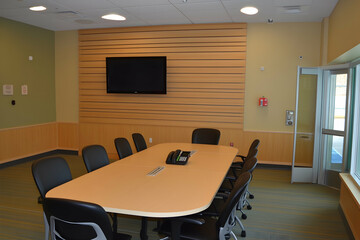 Modern conference room interior with a large table, chairs, and a flat-screen TV. Ideal for business meetings or presentations.