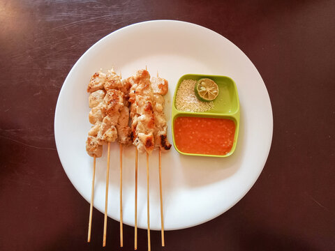 Sate Taichan. Grilled Chicken satay without peanut sauce and sweet soy sauce. Served on a plate with fresh chilli sauce.