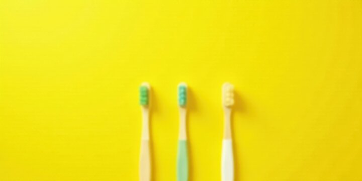 Brightly colored toothbrushes on yellow background, oral hygiene concept