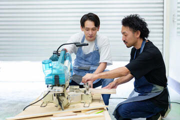 電動ノコギリを使って作業をする職人と弟子