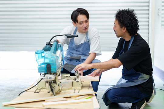 電動ノコギリを使って作業をする職人と弟子