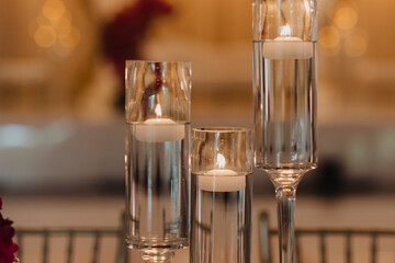 Elegant Cylindrical Glass Candleholders with Floating Candles at a Luxurious Wedding Reception