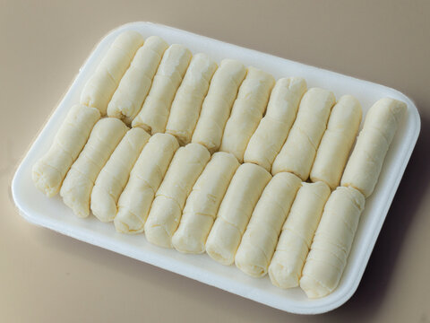 Detalle de deditos de queso y empanadas congeladas sobre una superficie texturizada, representando aperitivos tradicionales listos para preparar y disfrutar.