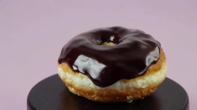 Chocolate cronut on a black pedestal, spotlighting glistening glaze and ripples for an indulgent luxurious visual
