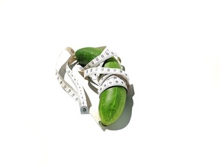 Cucumber fruit wrapped in a measuring device. Cucumbers and measuring tools on a white background