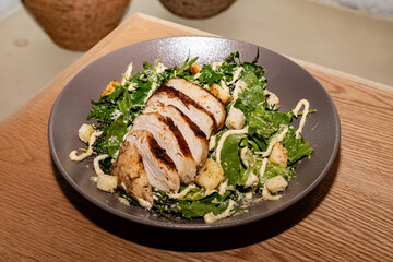 gourmet preparation of a delicious caesar salad with cheese, croutons, lettuce, arugula, parmesan cheese, caesar sauce and chicken medallions.