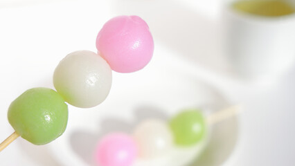 close-up of three-color mochi sweets and green tea on the white background