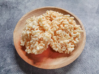 Rengginang or rice cracker, traditional snacks made from glutinous rice, savory and crunchy. Served on wooden plate. Indonesian food.