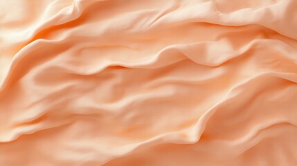 Soft peach fabric texture with elegant wavy folds and gentle shadows for background