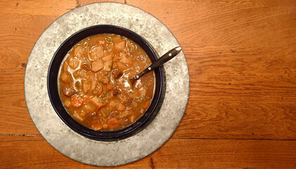 homemade paprika beef stew (Hungarian goulasch) in a blue bowl atop a galvanized charger on a distressed oak tabletop