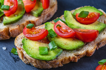 Avocado toast topped with tomato and green onion on a slice of carrot bread