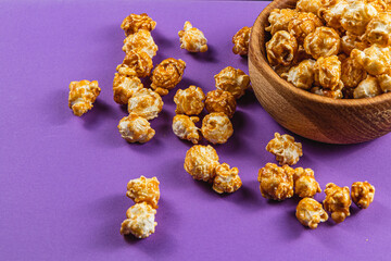 Sweet Caramelized Popcorn in a Wooden Bowl on a Purple Bright Background