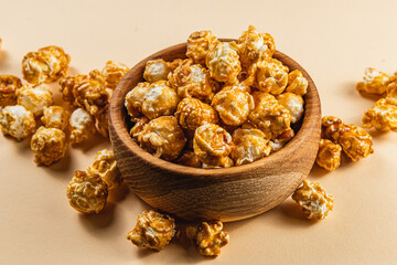Caramelized popcorn in a wooden bowl on a light background