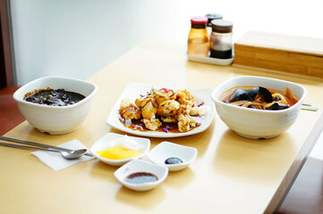 식탁 위에 짜장면 짬뽕 탕수육이 놓여 있는 모습