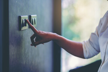 Woman's finger turn off on light switch at the wall. Energy saving concept. Selected focus	