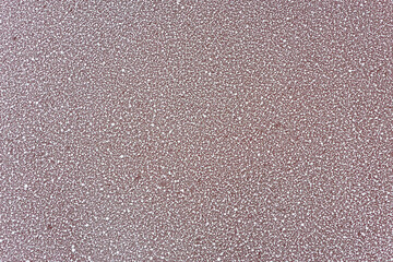 Close-up of textured red-tinted asphalt road surface with white speckles