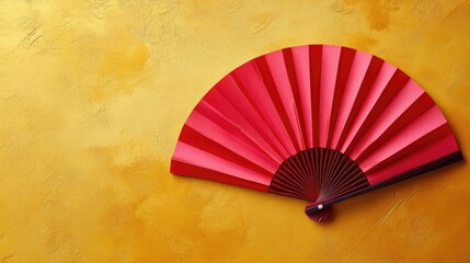 A minimalist composition of a red paper fan with intricate designs, set against a vibrant gold background.