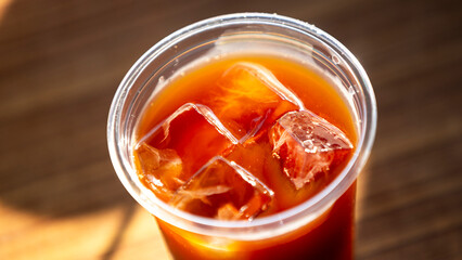 Iced coffee in plastic cup on wooden table. Close up.