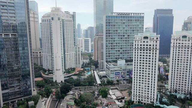 A sleek drone gracefully navigates through the concrete jungle of Jakarta, flitting between imposing skyscrapers. The bird's eye perspective is awesome.