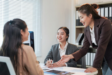 Three asian businesswomen are smiling and working together in a modern office, discussing charts...