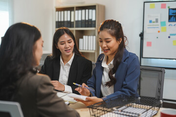 Three asian businesswomen are having a meeting in a modern office, discussing strategy and analyzing financial reports, fostering collaboration and teamwork for success