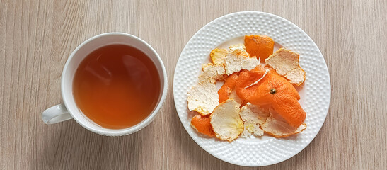A mug of tea and an orange peel on the table. The benefits of tangerine tea. Tea with mandarin peel. Citrus. Vitamin C.