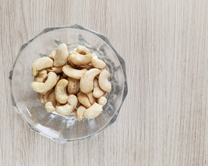 Glass transparent plate with cashews on a wooden table. Fatty amino acids in nuts. Fruits of the evergreen tropical tree Anacardium occidentale.
