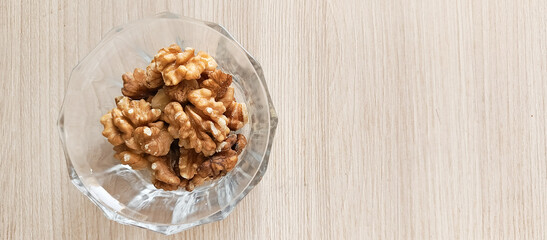Glass cup with walnuts on a wooden table top view. The benefits of nuts. Fat nuts.