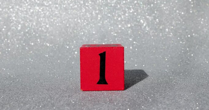 Footage of a red block with a silver glittery background showing the number 1 on a block being put down and taken back up again