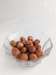Amino acids in hazelnuts. Hazelnuts in a glass cup on a white background. Fats, proteins, and dietary fiber in nuts. 