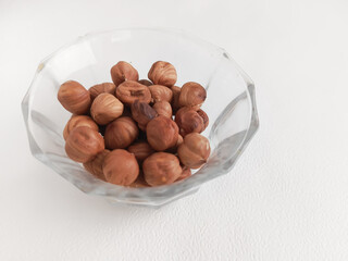 Amino acids in hazelnuts. Hazelnuts in a glass cup on a white background. Fats, proteins, and dietary fiber in nuts. 