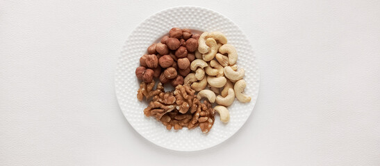 Walnuts, cashews, hazelnuts in a plate. Assorted nuts. Protein food. Food with a high protein content. Space for the text.