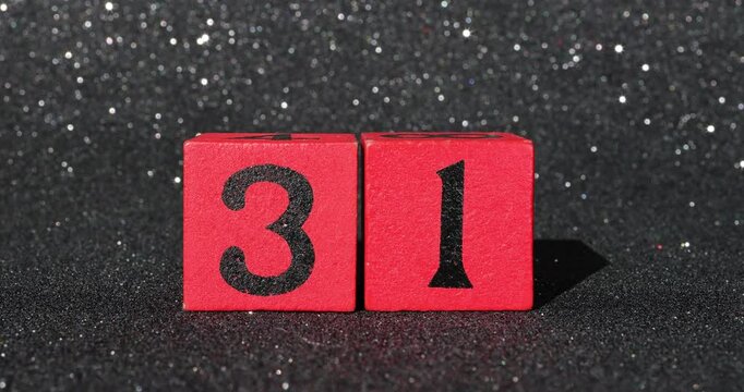 Footage of red blocks with the Date December 31st white is New Years Eve on a black glittery background showing the blocks being put down and taken back up again