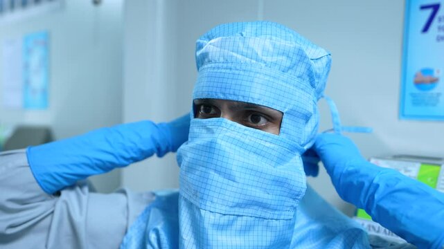 gowning process in medicine making, pharmaceutical factory. pharma worker changing clothes into PPE kit, in pharmaceutical production area cleanroom. pharmaceuticals process of entering into sterile.