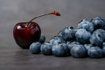 Closeup of blueberries and cherries on dark background.