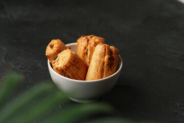 Bowl of freshly baked pastries with a golden crust on a dark surface