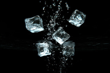 Ice cubes in motion with water droplets against a black background.