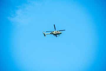 Helicopter is flying on isolated blue sky in mid-air background.
