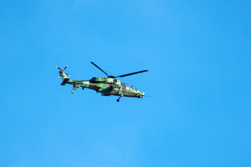 Helicopter is flying on isolated blue sky in mid-air background.