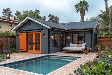 Fototapeta premium Cozy small barn-style operator's cabin with orange door, gray walls, white roof, brick walkway, outdoor pool, and California house with palm trees.